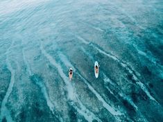 two people on surfboards in the middle of the ocean, looking at each other