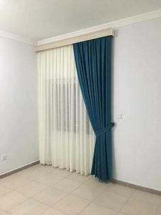 an empty room with blue curtains and tile flooring