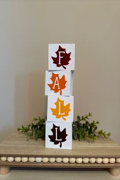 three wooden blocks with leaves on them and the letters f are painted in different colors