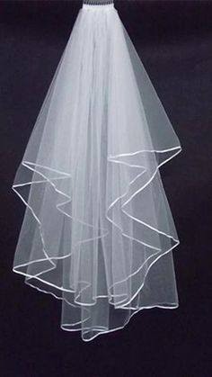 a white veil with ruffles on the bottom is hanging from a hanger