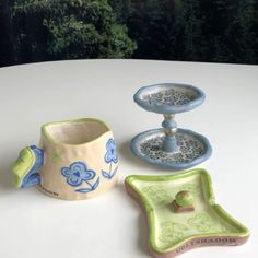 three ceramic dishes sitting on top of a white table next to each other and one has a blue flowered design