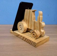 a wooden toy truck with a cell phone in it's holder on a table