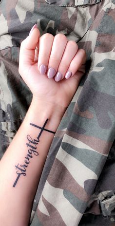 a woman's arm with a cross tattoo on it