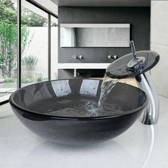 a black bowl shaped sink with water running from the faucet to it's side