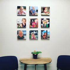 there are many pictures on the wall above two blue chairs and a small table with a potted plant