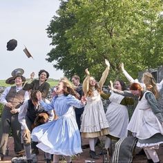 a group of people dressed in historical clothing are throwing hats into the air as they dance