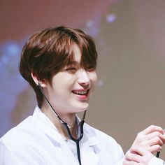 a young man wearing a stethoscope smiles at the camera while standing in front of a projection screen