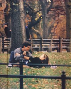 a man and woman sitting on the ground in a park