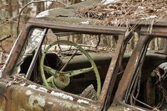 an old rusted out truck in the woods