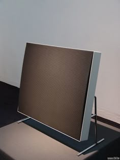 a black and white photo of a large monitor on a stand next to a wall