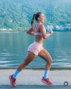 a woman running by the water wearing pink shorts