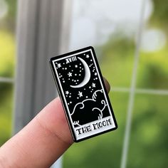 the moon tarot card sticker is on someone's finger, in front of a window