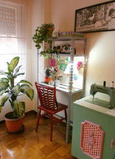 a room with a sewing machine, potted plant and window