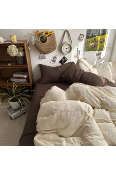 an unmade bed with brown and white comforter in a bedroom next to a book shelf