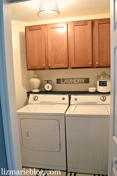 a washer and dryer sitting in a laundry room next to wooden cupboards