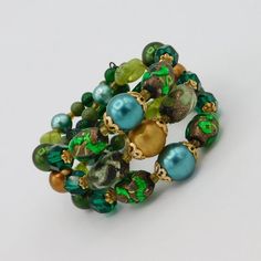 Pretty artisan made wire cuff bracelet easily fits a a 7-8 inch wrist.  Made with beautiful selection of irredescent green art glass beads, faceted green glass beads, satin finished beads and round glass beads about to finish out the ends.  Large beads of gold tone filigree bead caps.  The color combination is wonderful with bright green foil glass and varying shades of green and gold satin finished beads.  Bracelet is 1 1/4 inch wide and in very good vintage condition. Green Bohemian Wrap Bracelet With Round Beads, Bohemian Green Wrap Bracelet With Round Beads, Adjustable Green Wrap Bracelet With Round Beads, Bohemian Green Bracelets With Spacer Beads, Green Bohemian Stretch Bracelet With Faceted Beads, Green Hand Wrapped Beads For Jewelry Making, Bohemian Green Bracelet With Spacer Beads, Green Round Beaded Bracelets For Party, Green Large Beads For Party