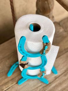 a roll of toilet paper sitting on top of a wooden floor next to a spool of yarn