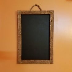 a chalkboard hanging on the wall next to a toilet in a room with orange walls