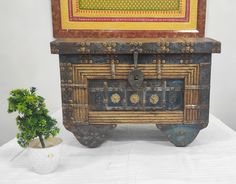 an old trunk sitting next to a small potted plant on top of a table