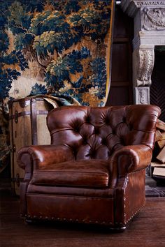 a brown leather chair sitting in front of a fireplace