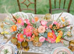 the table is set with colorful flowers and goldware for an elegant dinner party or reception