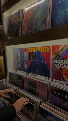 a woman looking at records on display in a music store, with the caption starboy