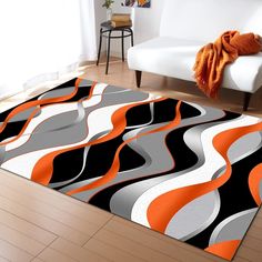 a living room area rug with an orange and black design on the floor next to a white couch