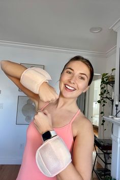 a woman in pink tank top and white gloves holding up her arm with one hand