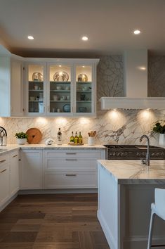 a kitchen with white cabinets and marble counter tops