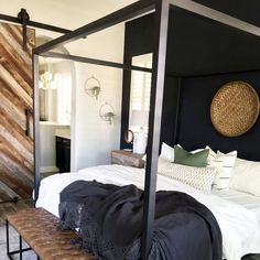 a four poster bed with white sheets and black headboard is in the middle of a room