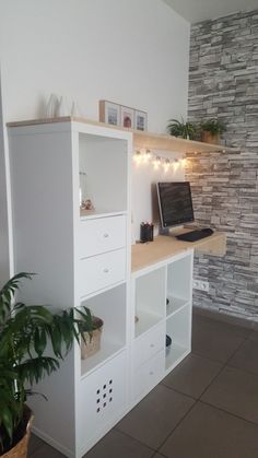 a laptop computer sitting on top of a white shelf next to a plant and potted plant