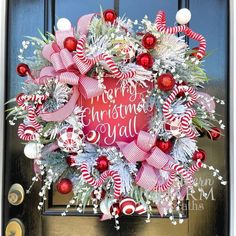 a christmas wreath with candy canes and ornaments hanging on the front door to say merry christmas y'all