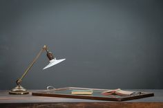 a desk lamp sitting on top of a wooden table next to a tray with books