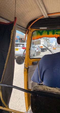 a man sitting in the driver seat of a small yellow vehicle with an open door