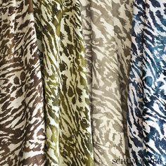 several different colored animal print fabrics hanging on a clothes rack in a store or showroom