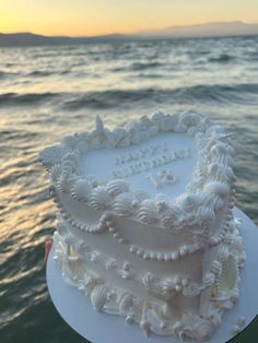 a white cake sitting on top of a plate near the ocean