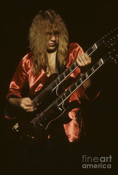 a man with long hair playing an electric guitar in front of a black background canvas print