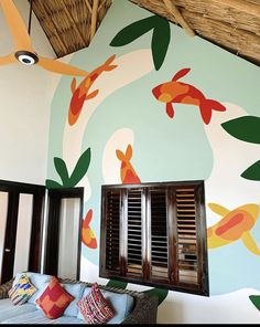 a living room with fish painted on the wall and windows in it's center