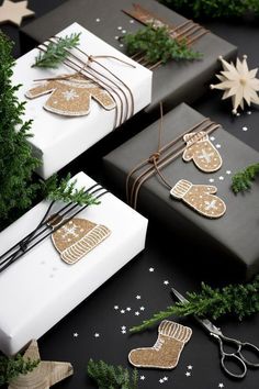 christmas presents wrapped in black and white paper with gold foiled mittens on them