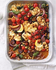 a pan filled with chicken, vegetables and chickpeas on top of a table