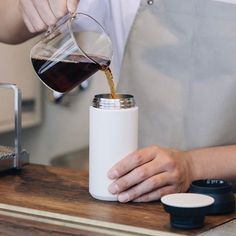 a person pouring coffee into a white cup