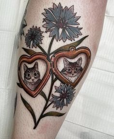 a woman's leg with two cats in heart shaped frames and flowers on it