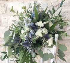 a bouquet of flowers sitting on top of a white chair next to a brick wall