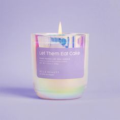 a candle that is sitting in front of a purple background with the words let them eat cake on it