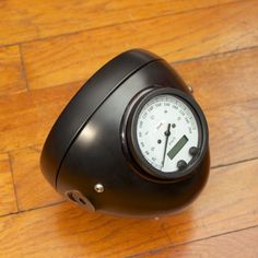 a black motorcycle helmet sitting on top of a wooden floor next to a speedometer