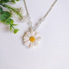 a necklace with a flower on it next to some flowers