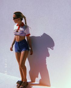 a woman standing in front of a white wall with her shadow on the wall behind her