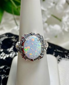 The oval high-quality simulated rainbow white opal is 12mm by 10mm (just shy of 3/8" inch) in dimension... The ring is 5/8th of an inch (16.5mm) NS (long) on the finger. The ring and gem sit 7mm off the finger. The inside of the band is marked 925 for sterling. Notice the beautiful filigree swirl like the craftsmanship of the silver setting. Opal Art, Rainbow Ring, Rainbow Rings, Leaf Garland, White Opal, Solitaire Ring, Cuff Bracelets, Swirl, Art Nouveau