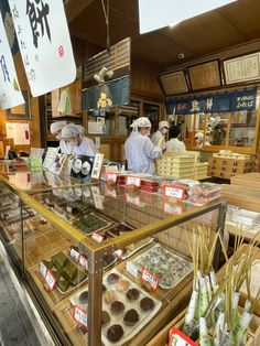 some people are standing in front of a counter with sushi and other food items