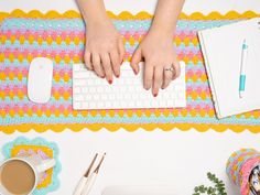 a woman's hands typing on a computer keyboard next to a cup of coffee